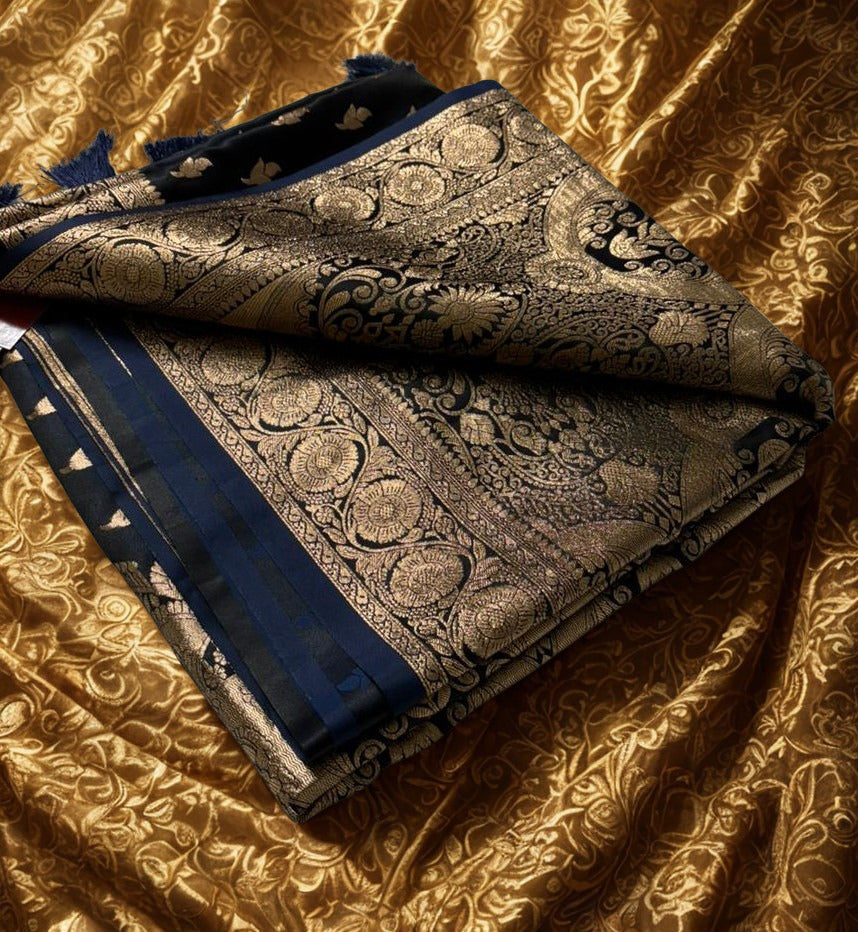 Folded Navy blue Banarasi Silk Saree with intricate zari work placed over a gold textured background