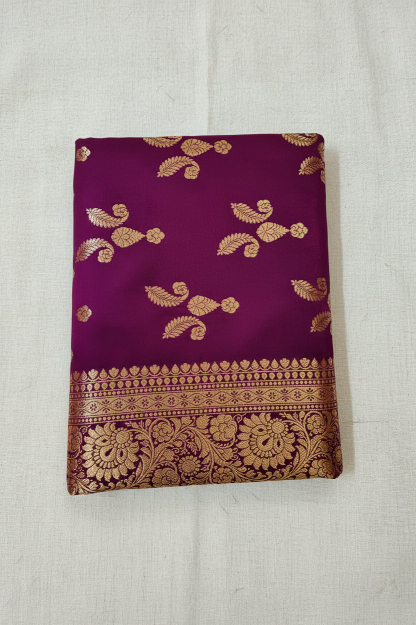 A folded Wine purple Dual-tone silk Banarasi saree with intricate gold zari embroidery and a wide decorative border, displayed on a light blue textured background.