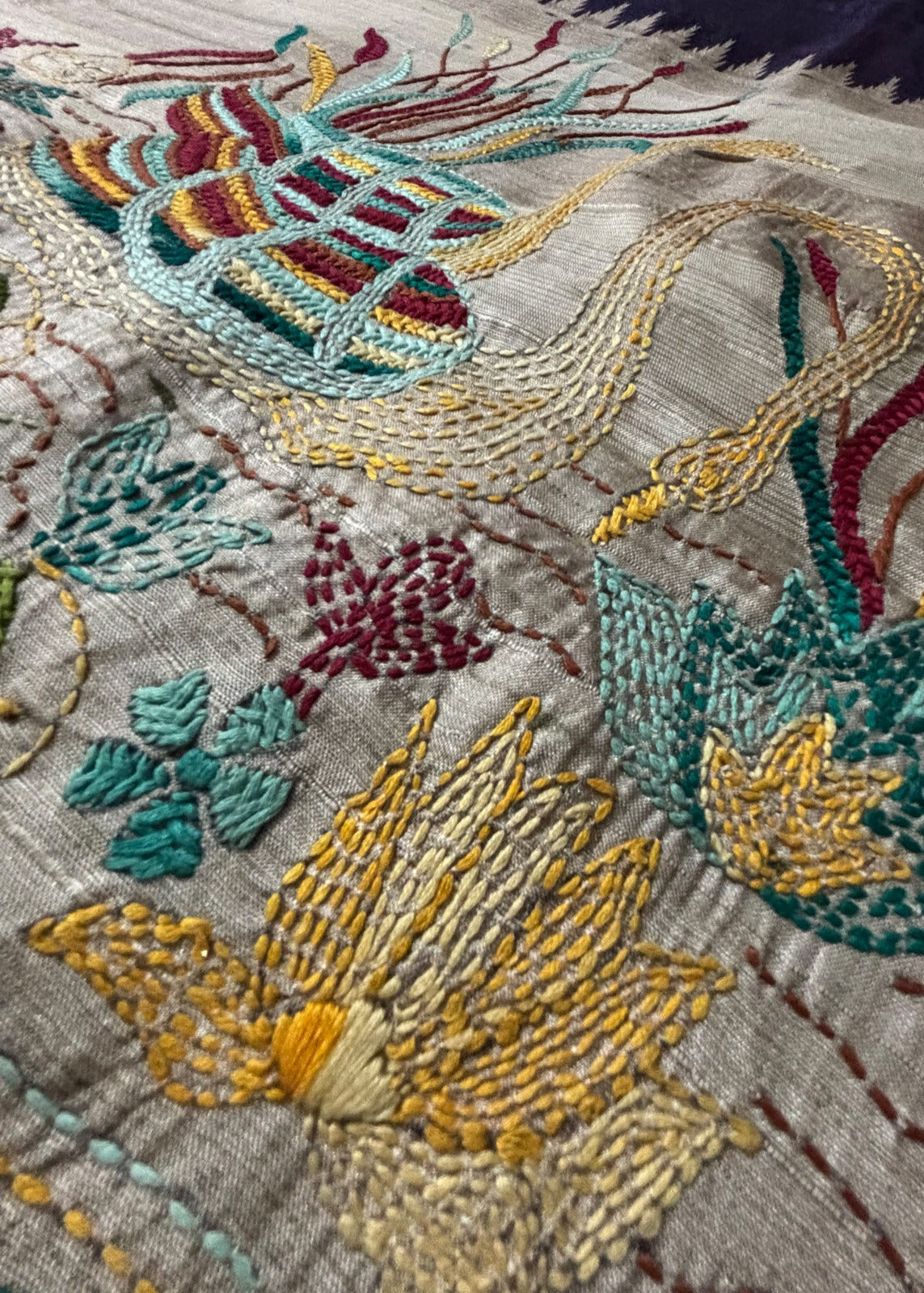 Close-up of two hand-embroidered Kantha swans in a lotus pond on beige saree pallu