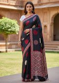 Woman wearing a black Ajrakh saree with red circle polka patterns in an outdoor setting