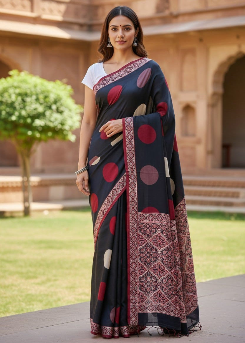 Woman wearing a black Ajrakh saree with red circle polka patterns in an outdoor setting
