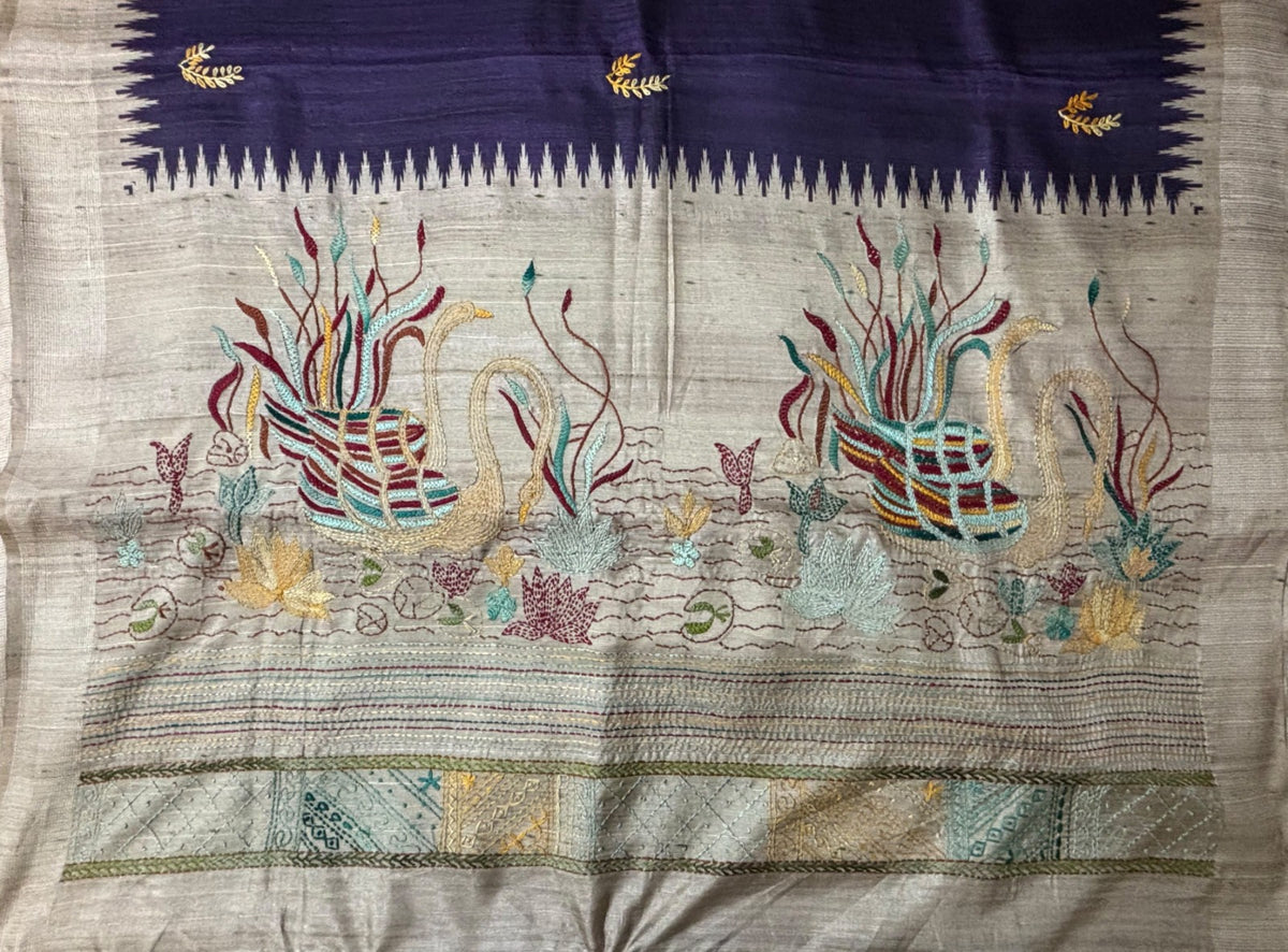Close-up of two hand-embroidered Kantha swans in a lotus pond on beige saree pallu
