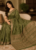 Full-length view of a woman wearing an imperial moss green Baluchari silk saree with delicate gold small buti motifs, a rich gold border, and a lavishly woven pallu depicting classic mythological figures and intricate royal patterns