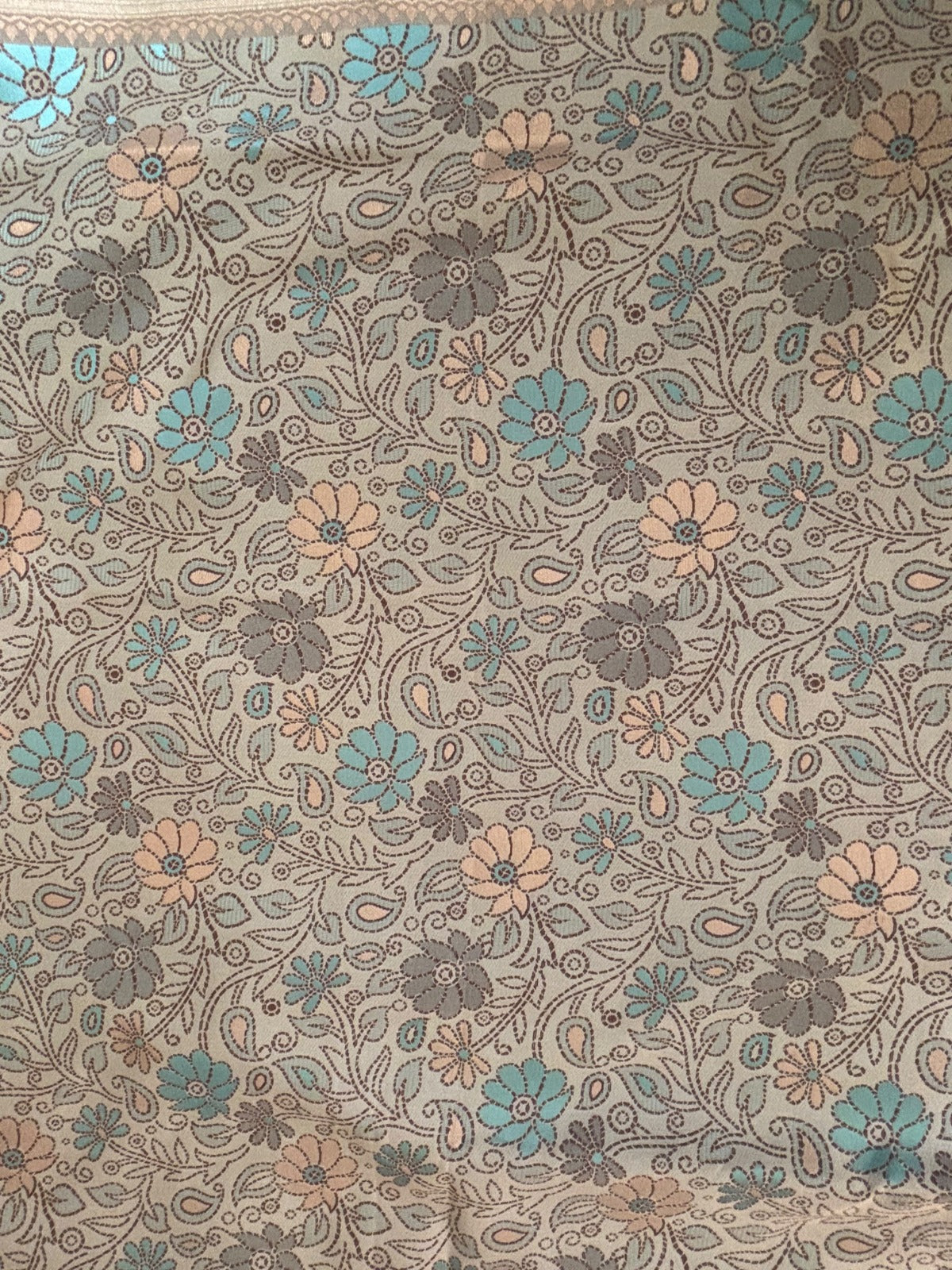 A close-up of Banarasi Saree Body with an all-over floral and paisley pattern in muted blue, peach, and gray tones.