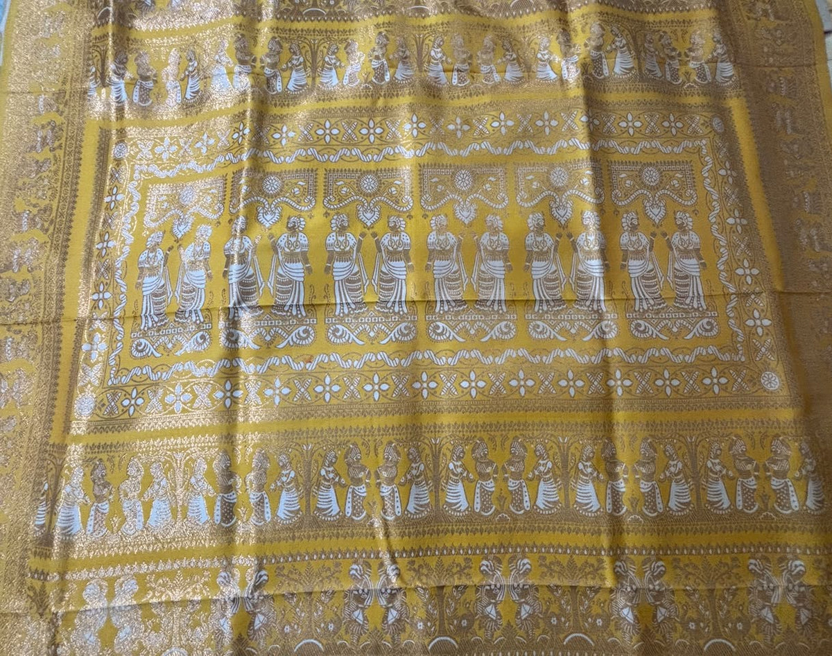 A close-up of a yellow Pallu with intricate silver and white woven patterns depicting figures and traditional motifs.
