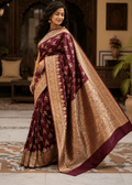 Deep maroon handwoven Banarasi silk saree with gold zari floral booti motifs and intricate woven border, draped on model