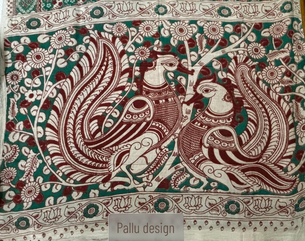 A premium teal-green and rust-red cotton Kalamkari saree with a detailed peacock and tree-of-life motif pallu.