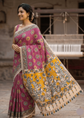 A woman smiling while wearing the Mayurika premium magenta pink cotton Kalamkari saree featuring a contrasting mustard yellow pallu with traditional peacock and lotus motifs