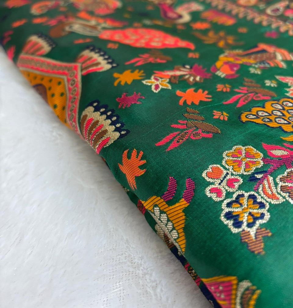 Colorful embroidered Baluchari Saree with floral and animal patterns on a green background