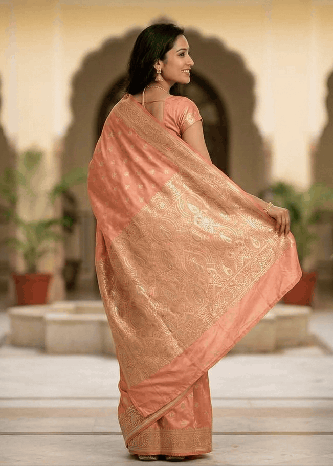 Woman wearing peach Banarasi silk saree with gold paisley pallu for wedding occasion