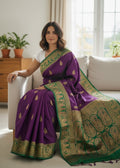 Woman wearing Rajrangini Baluchari silk saree in royal purple with green and gold zari border, elegant traditional Indian handloom saree for festive and wedding occasions