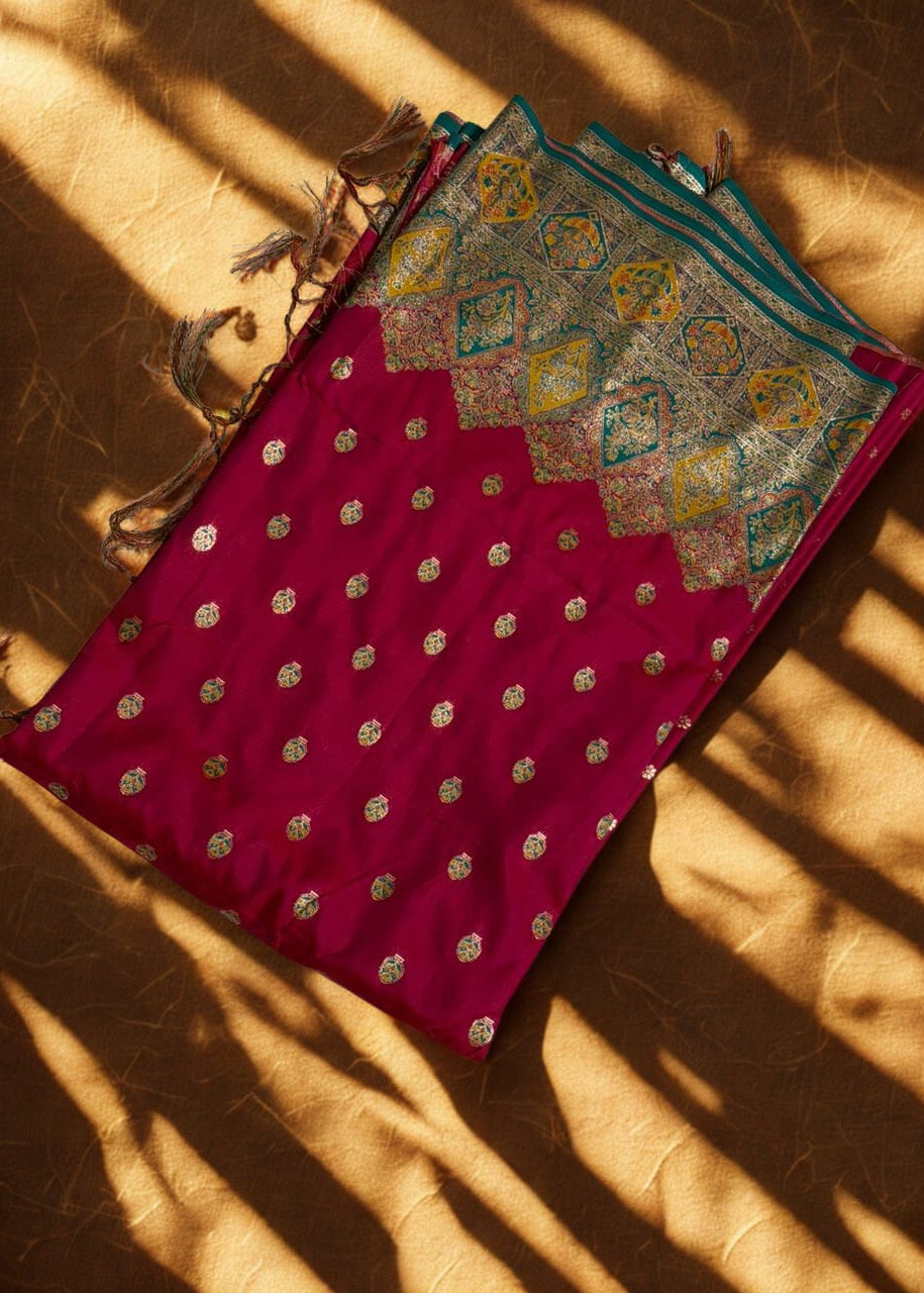 Red Baluchari saree with gold patterns on a textured brown surface