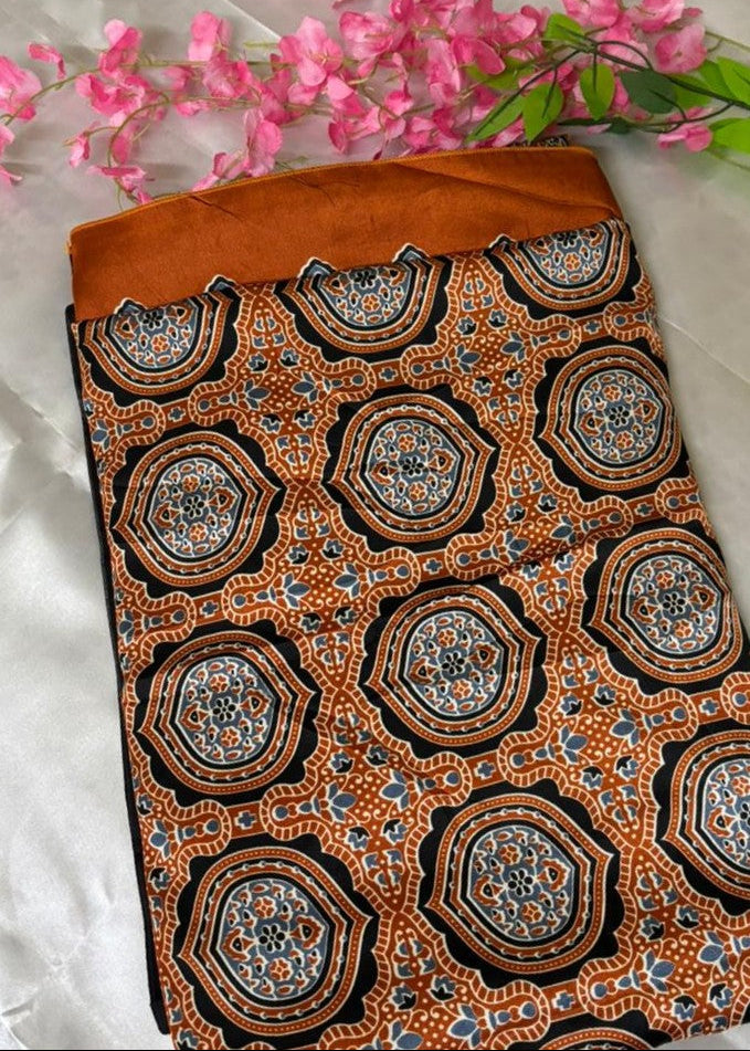 A Orange Modal Silk saree with Ajrakh Geometrical print placed above a white satin cloth