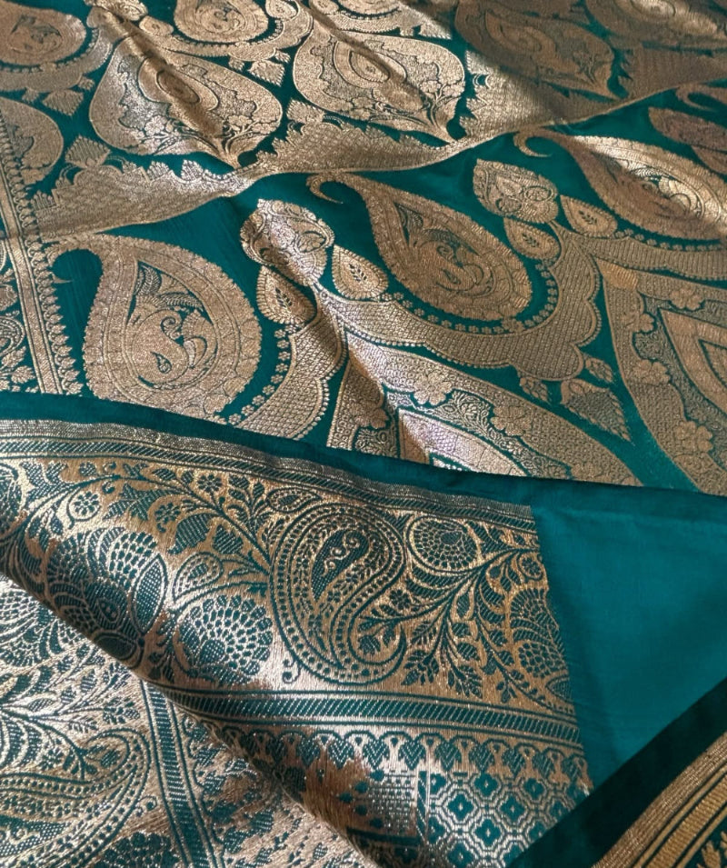Teal green Banarasi silk saree flat lay showing full gold zari buti body and oversized paisley zari pallu