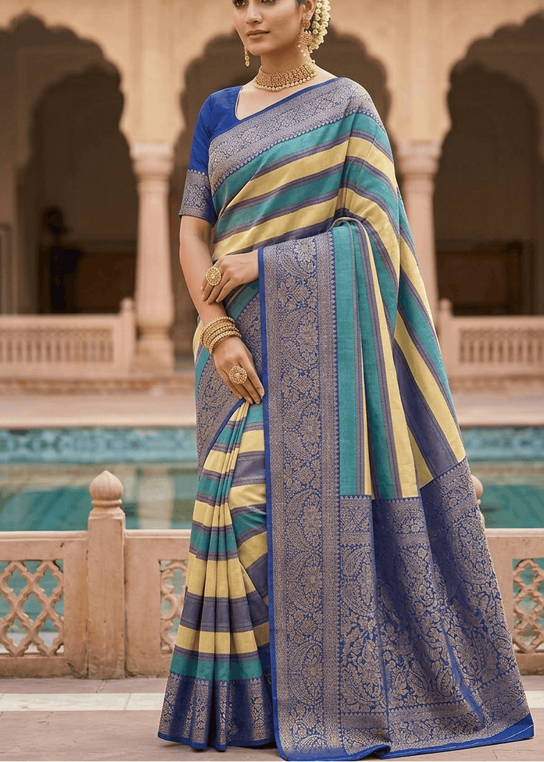 Woman wearing an indigo, mustard and teal striped zari saree with paisley pallu in a sandstone haveli