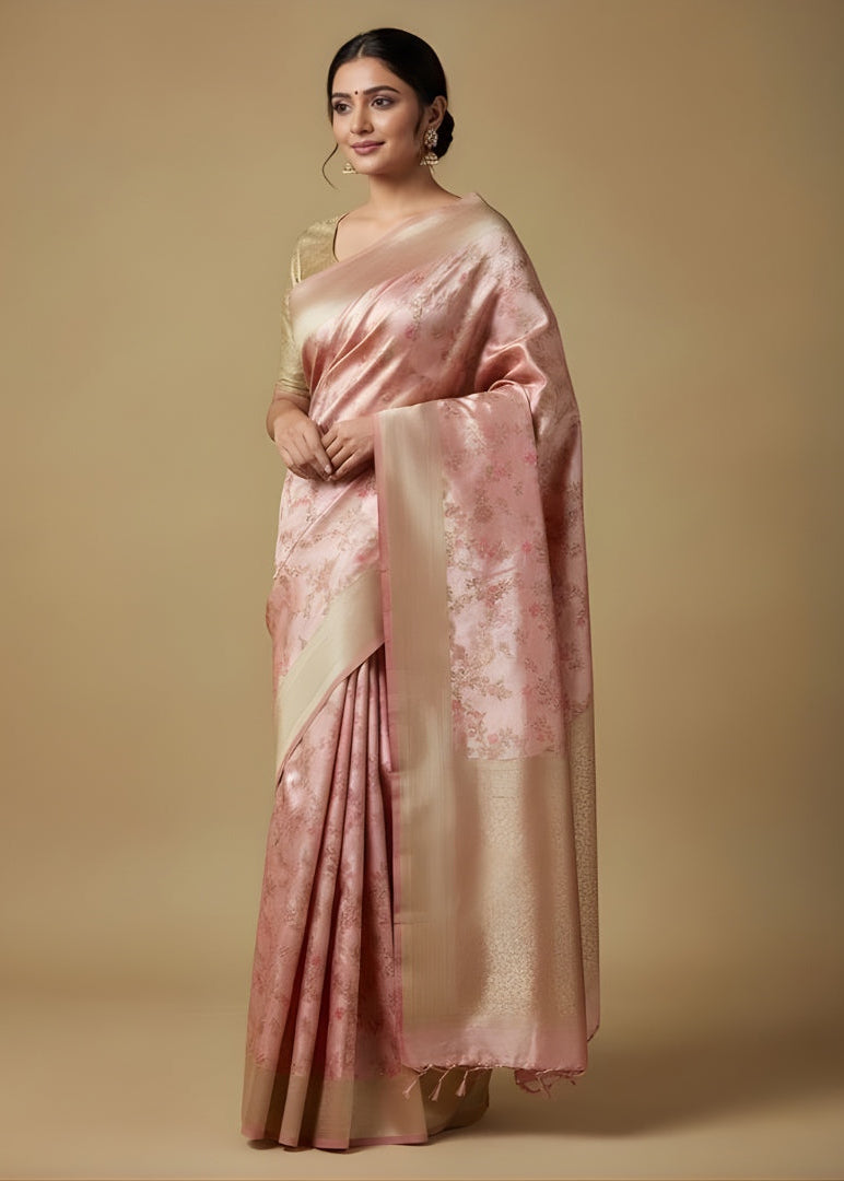 Woman wearing a pink Banarasi saree with a gold border on a beige background