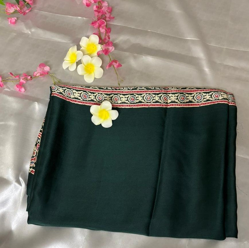 Dark green modal silk azrakh saree fabric with decorative border and flowers on a light gray background