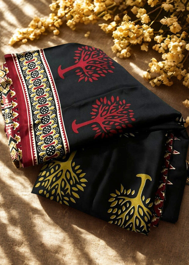 Folded Modal silk azrakh saree with tree patterns on a textured surface with yellow flowers.