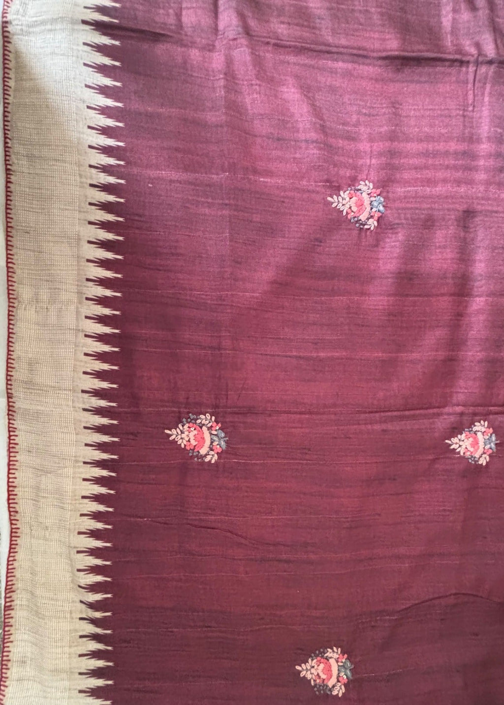 A close-up of a deep marron Beige coloured Boolian kantha Saree, featuring a cream-colored zigzag border on the left and small pink and green floral motifs scattered across the body.
